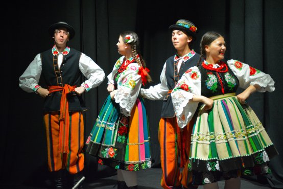 Koncert wiosenny Zespołu Pieśni i Tańca Boruta , grupa młodzieży tańczy i śpiewa  na scenie 