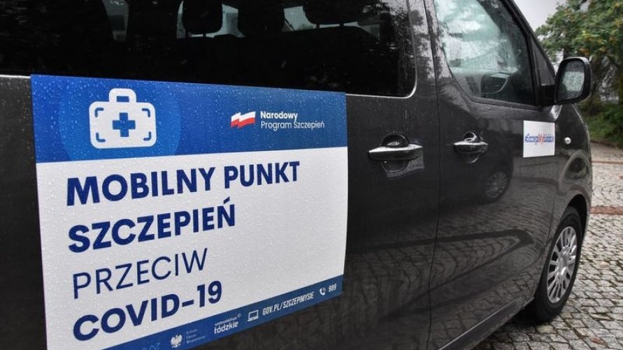 Szczepieniobus - zdjęcie boku ciemnego busa, opatrzonego naklejką z napisem: mobilny punkt szczepień przeciw COVID-19